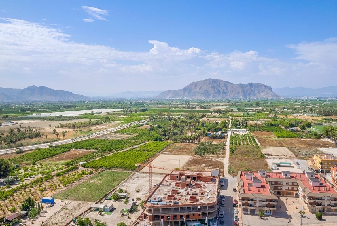 Stunning aerial view of modern new build 3-bedroom apartment in Jacarilla with panoramic open views of lush countryside and mountains.