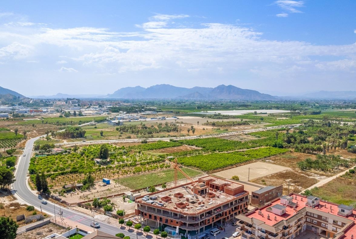 Expansive aerial view of new build 3-bedroom penthouse under construction with sunlit terrace and panoramic open countryside views in Jacarilla