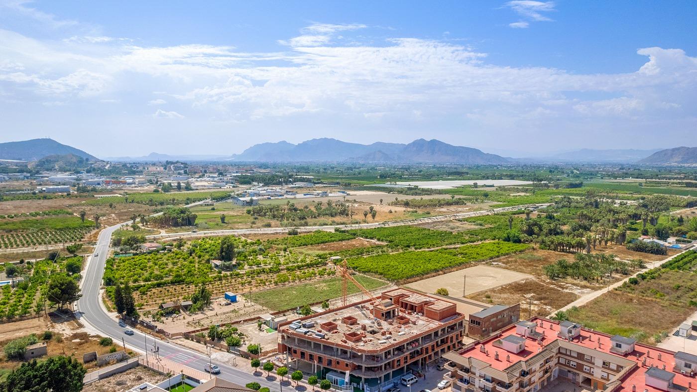Expansive aerial view of new build 3-bedroom penthouse under construction with sunlit terrace and panoramic open countryside views in Jacarilla