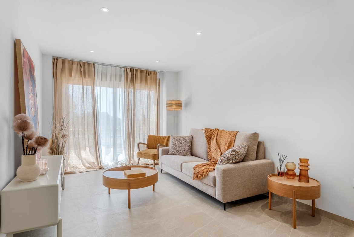 Bright, modern living room with light-toned furnishings and sheer curtains in a new 3-bedroom apartment with open views in Jacarilla.