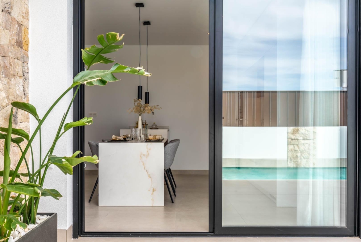 Bright open-plan dining area with modern marble table and sleek chairs, overlooking the private pool of a Mediterranean villa in Roldán.