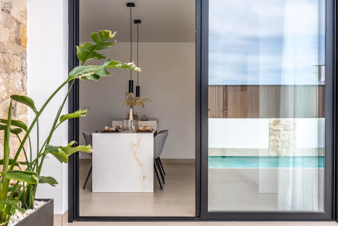 Bright open-plan dining area with modern marble table and sleek chairs, overlooking the private pool of a Mediterranean villa in Roldán.