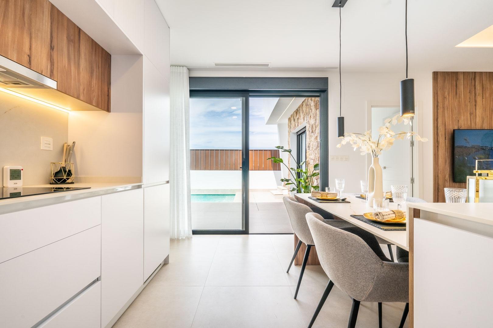 Bright, modern open-plan kitchen and dining area with sliding doors opening to a private pool at Mediterranean villa in Roldán.