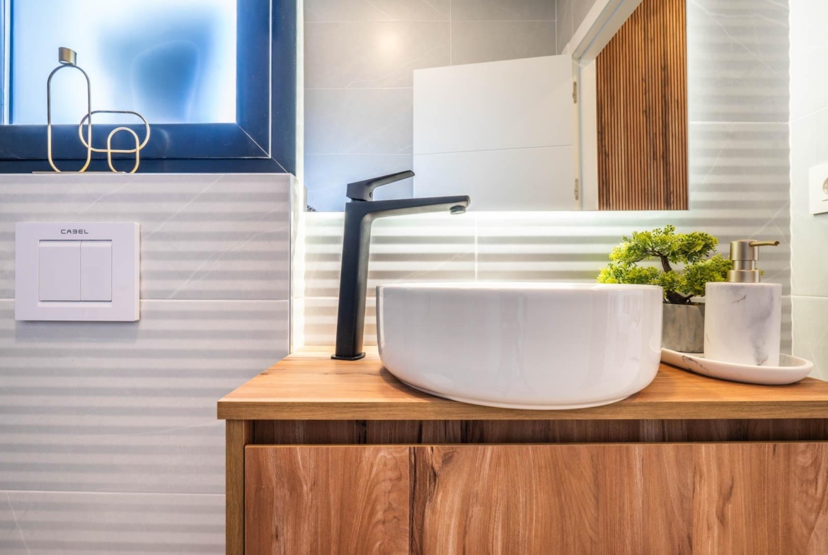 Modern bathroom vanity with sleek black faucet and natural wood cabinetry in Mediterranean single-storey villa, Roldán Torre-Pacheco.