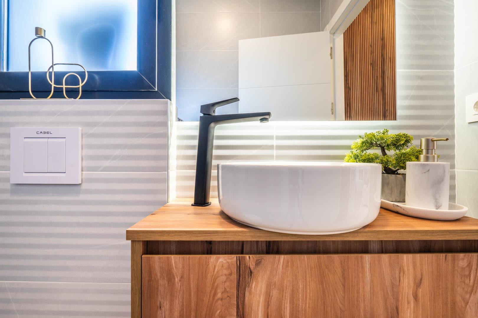Modern bathroom vanity with sleek black faucet and natural wood cabinetry in Mediterranean single-storey villa, Roldán Torre-Pacheco.