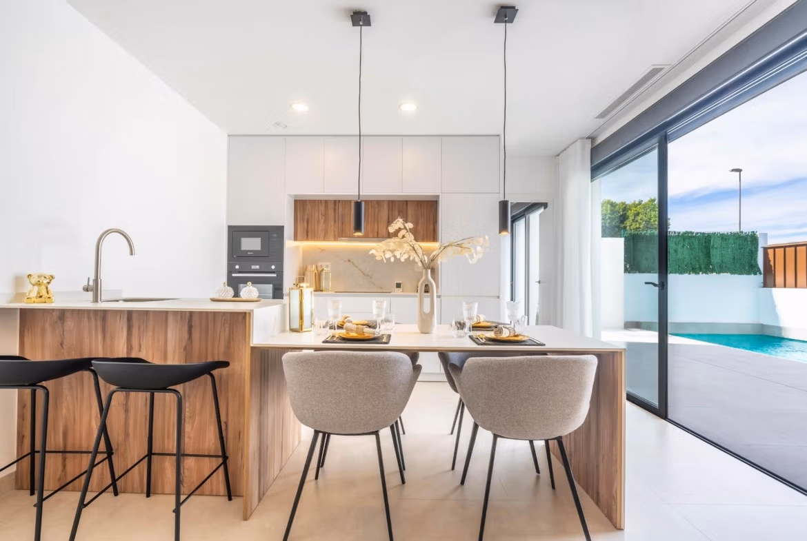 Bright open-plan kitchen and dining area with stylish wood accents and sliding doors opening to a private pool in Roldán villa.