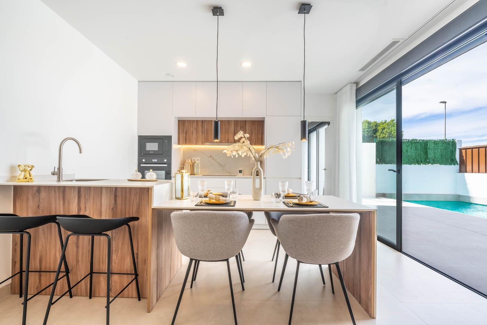 Bright open-plan kitchen and dining area with stylish wood accents and sliding doors opening to a private pool in Roldán villa.