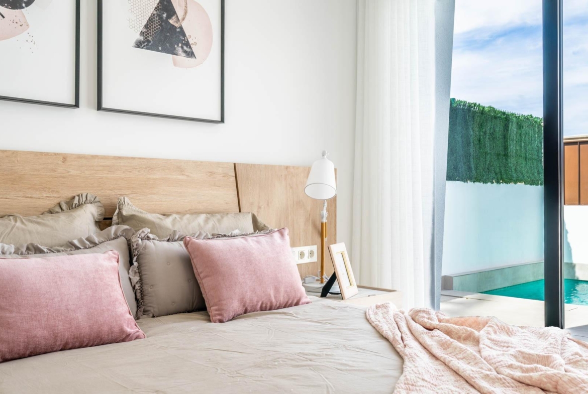 Bright and elegant bedroom with soft pastel accents and sliding doors opening to a private pool at Mediterranean villa in Roldán.