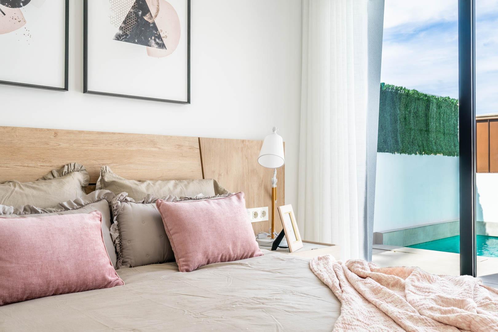 Bright and elegant bedroom with soft pastel accents and sliding doors opening to a private pool at Mediterranean villa in Roldán.