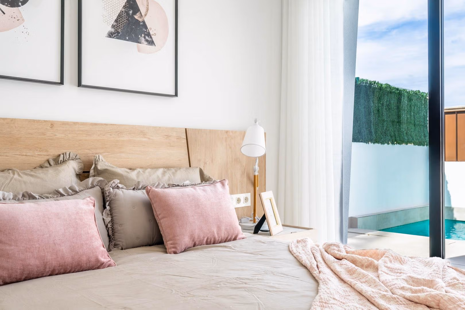 Bright and elegant bedroom with soft pastel accents and sliding doors opening to a private pool at Mediterranean villa in Roldán.