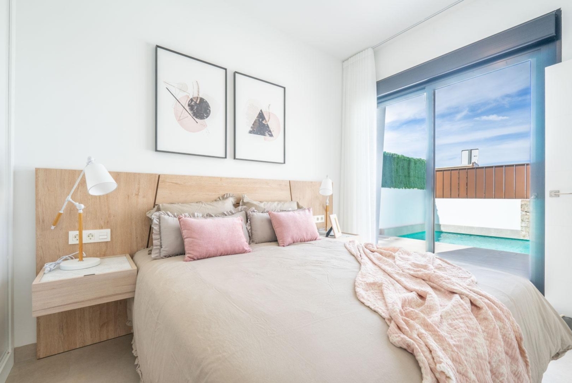 Bright, elegant bedroom with soft tones and private pool visible through glass door in Mediterranean single-storey villa, Roldán, Torre-Pacheco.