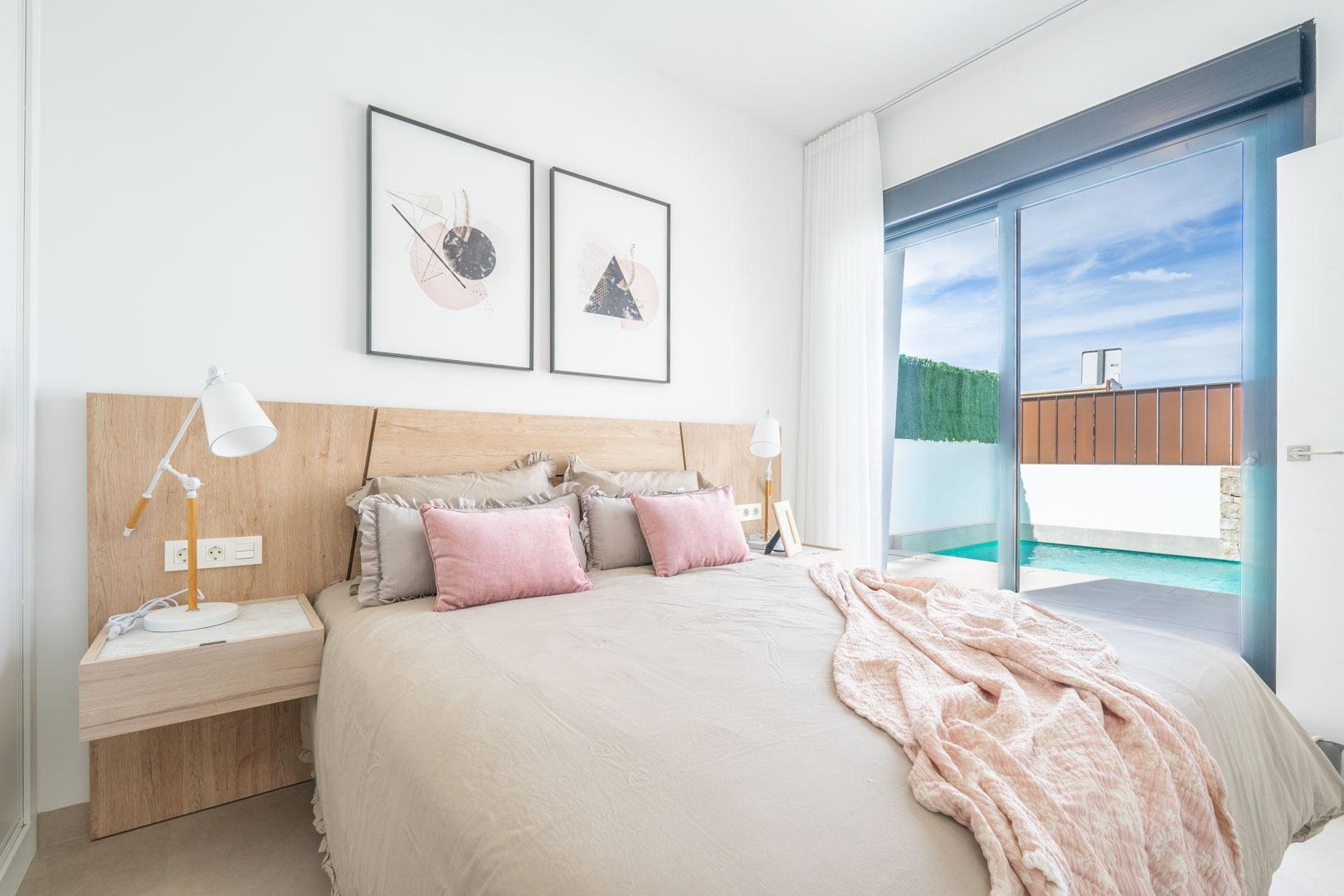 Bright, elegant bedroom with soft tones and private pool visible through glass door in Mediterranean single-storey villa, Roldán, Torre-Pacheco.