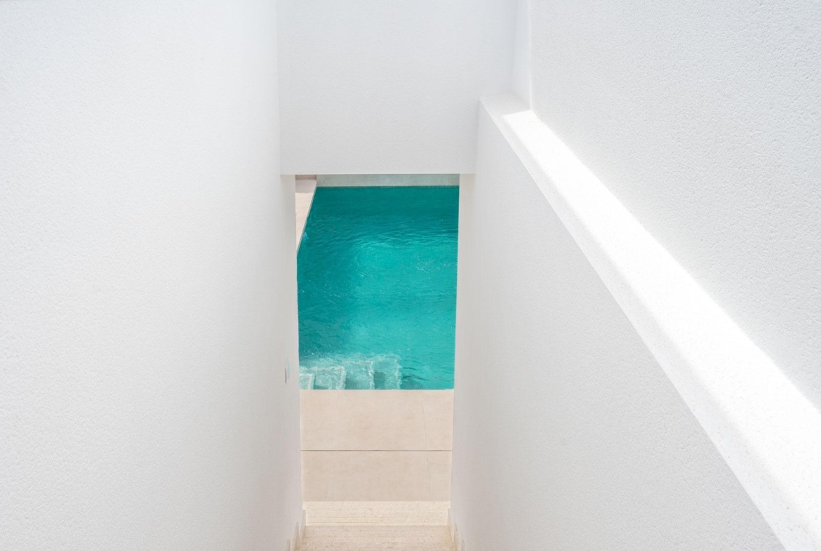 Bright, minimalist staircase leading to a private turquoise pool in a modern Mediterranean single-storey villa in Roldán, Torre-Pacheco.