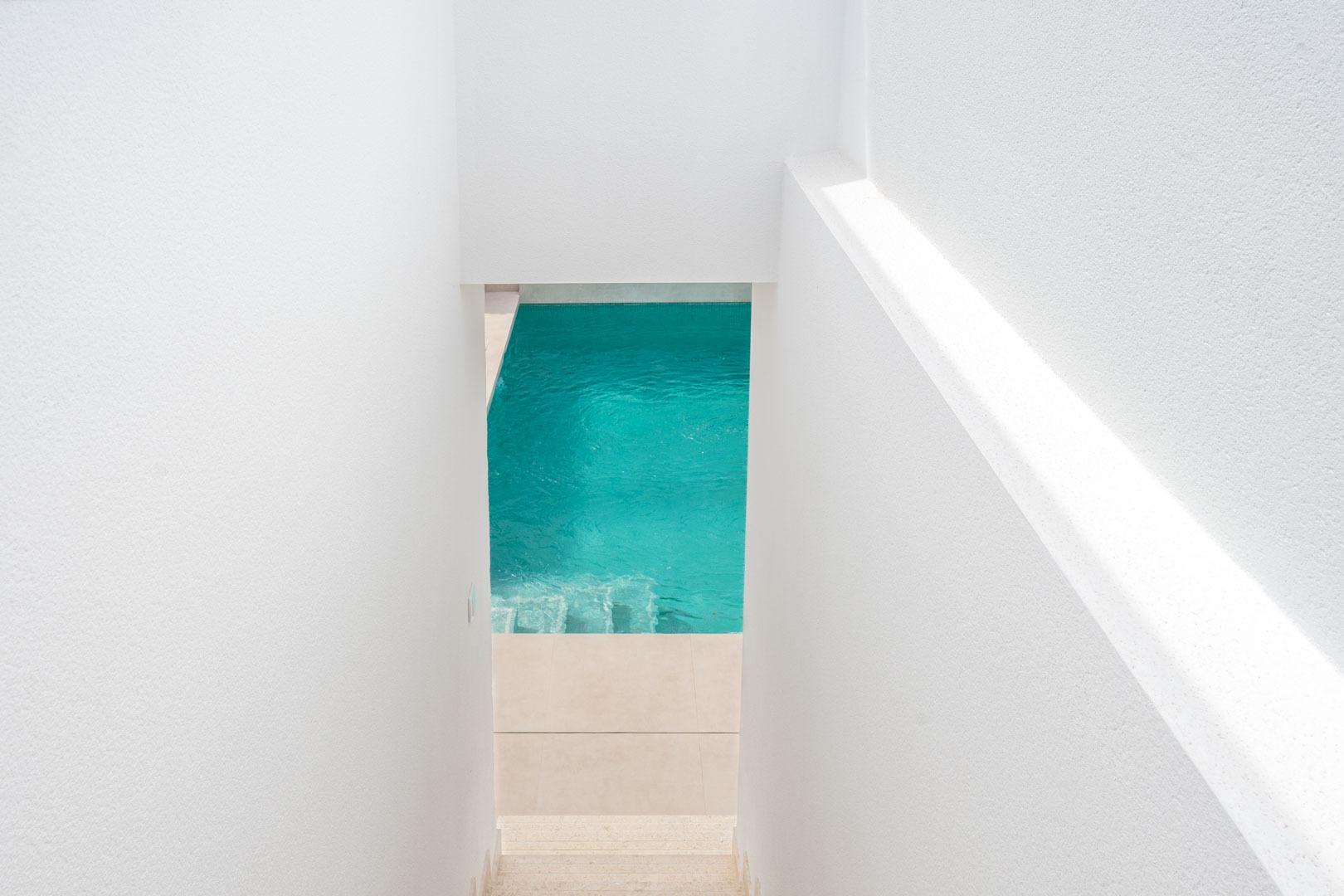Bright, minimalist staircase leading to a private turquoise pool in a modern Mediterranean single-storey villa in Roldán, Torre-Pacheco.