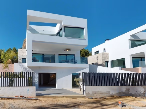 Modern, sleek 3-bedroom luxury villa under clear blue sky in Polop, featuring spacious terraces and glass balcony railings.