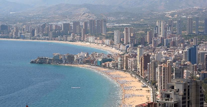 Panoramic sun-drenched beach and cityscape of Benidorm showcasing a vibrant coastal lifestyle near luxury villas.