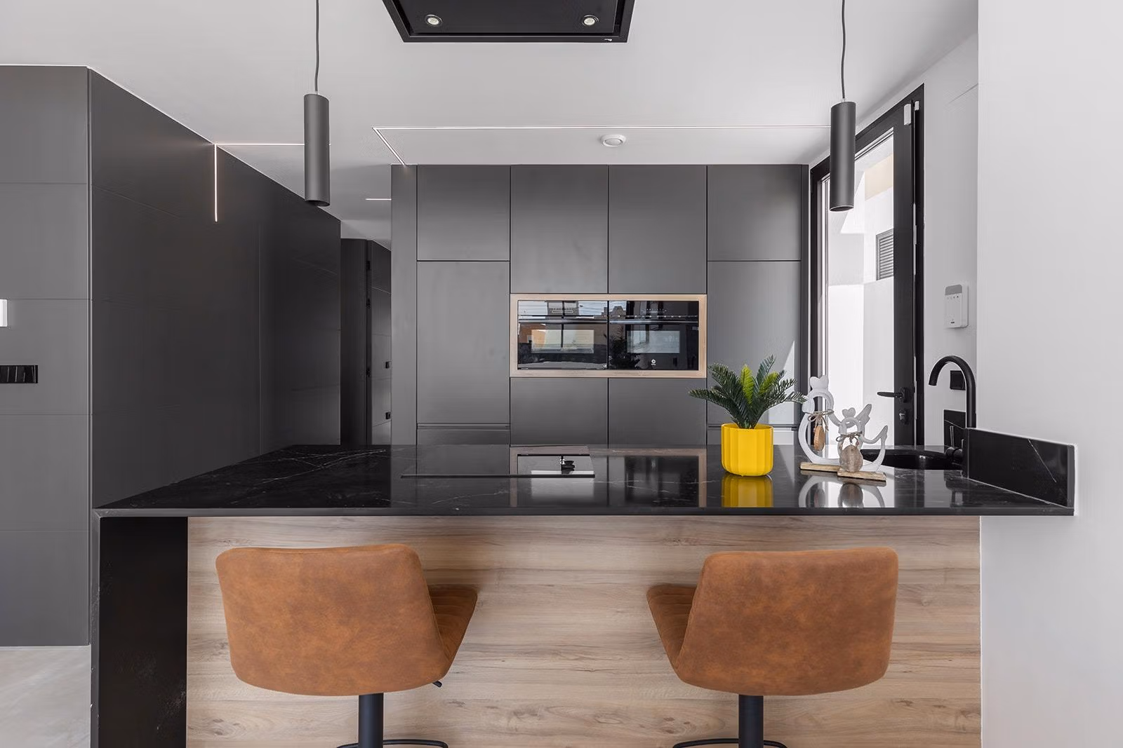 New-Build-One-Story-Villas-with-Private-Pool-in-Torrevieja-22 Modern kitchen with sleek black countertops and brown leather stools in key-ready single-storey villa in Los Balcones, Torrevieja