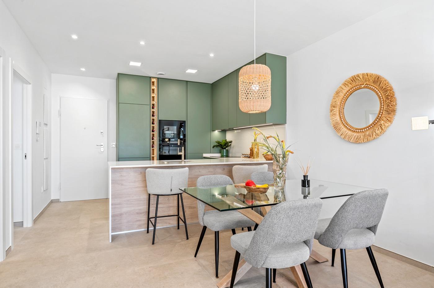 Bright open-plan kitchen and dining area with modern green cabinetry in a luxury 2-bedroom ground floor apartment, Serena Golf, Los Alcazares