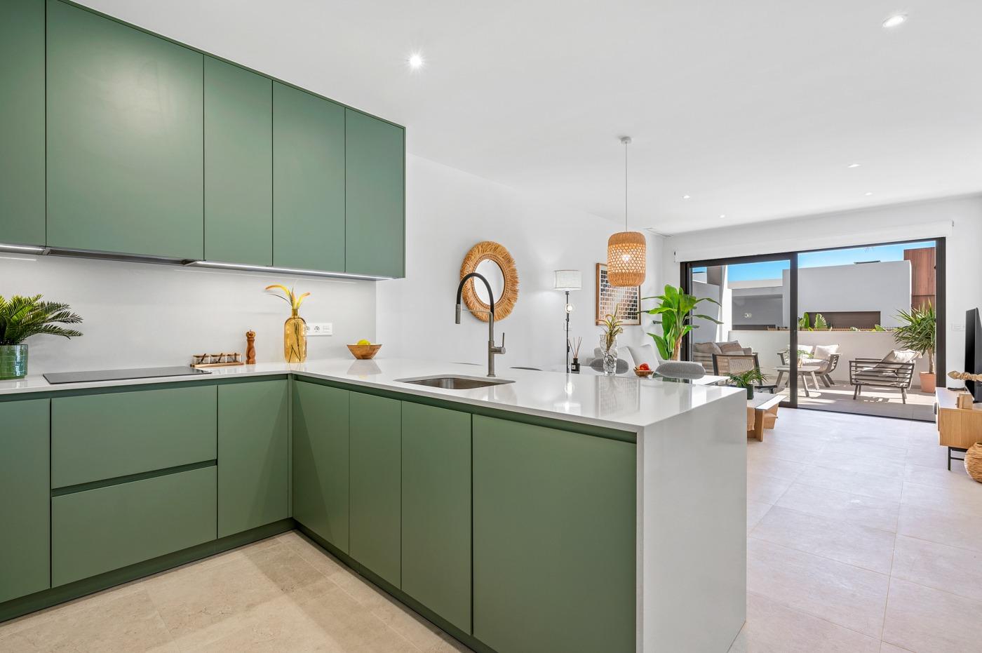 Modern new build 2-bedroom ground floor apartment kitchen with sleek cabinetry and bright open-plan living opening to garden terrace in Serena Golf, Los Alcazares.