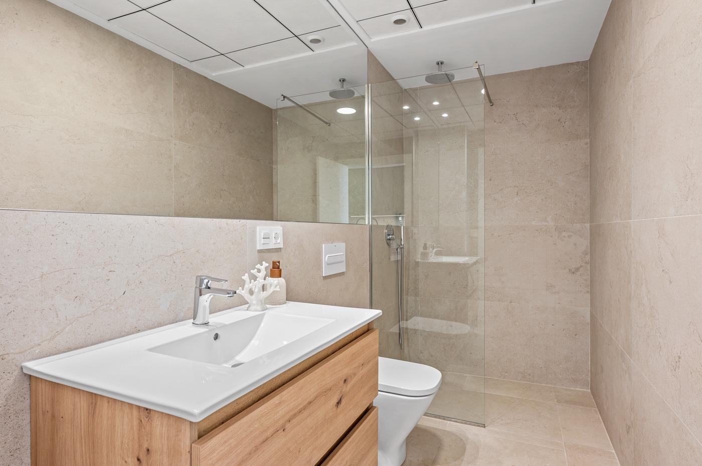 Elegant modern bathroom with sleek fixtures and glass shower in a 2-bedroom ground floor apartment with garden in Serena Golf, Los Alcazares