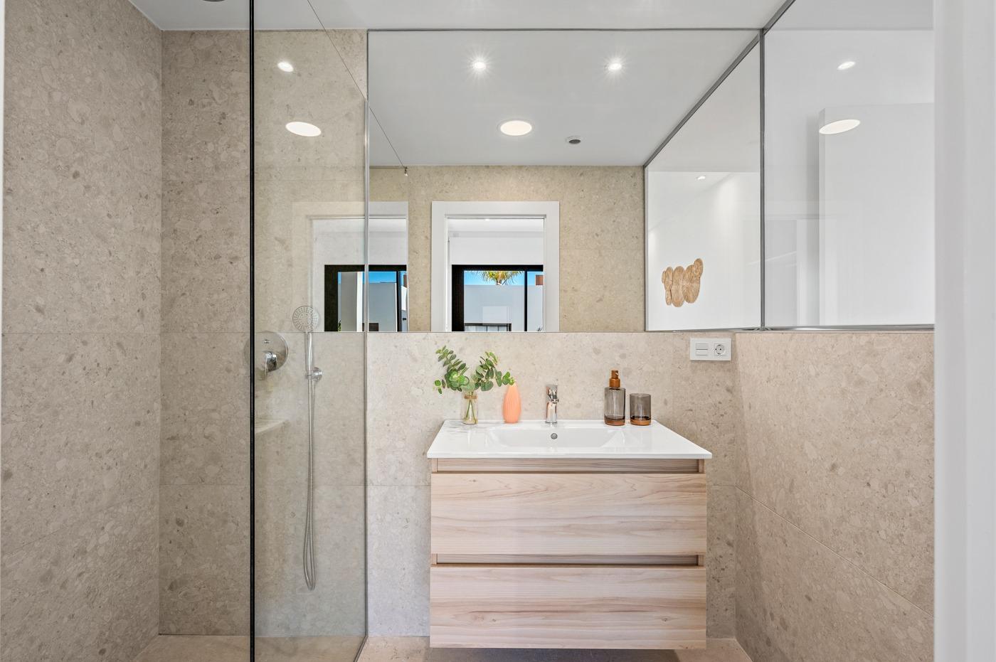 Modern, sleek bathroom with glass shower and light wood vanity in 2-bedroom ground floor apartment in Serena Golf, Los Alcazares.