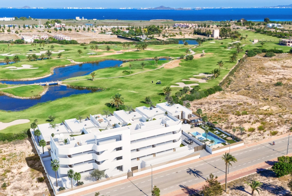 Modern white new build apartment complex with terraces overlooking lush Serena Golf course and sparkling Mediterranean Sea in Los Alcazares.