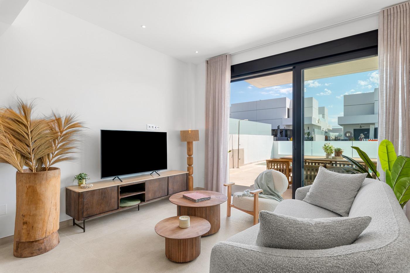 Bright, modern living room with sliding glass doors opening to a sunlit terrace in a spacious 3-bedroom semi-detached villa in Dolores, Alicante.