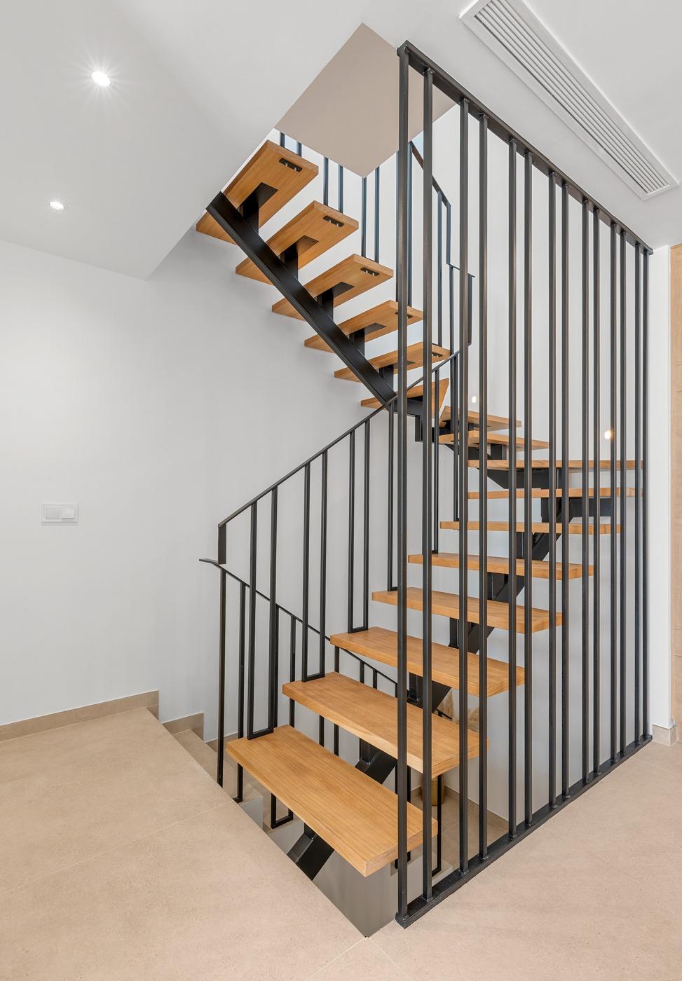 Modern open staircase with sleek wood steps and black metal railing in spacious new build 3-bedroom villa in Dolores, Alicante