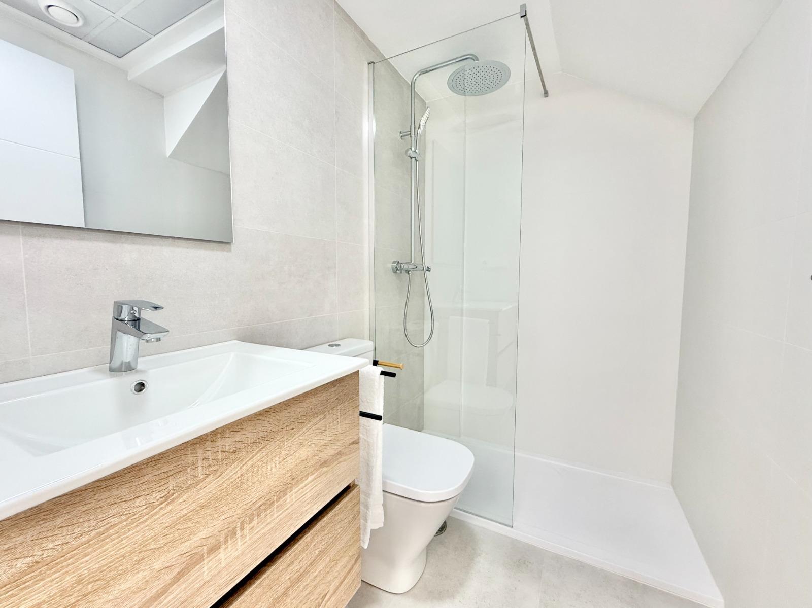 Bright modern bathroom with sleek wooden vanity and rain shower in spacious new build 3-bedroom townhouse in Cox, Alicante