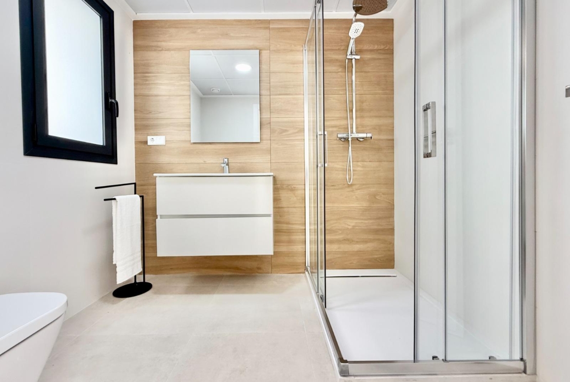 Modern, bright bathroom with sleek glass shower and wood-effect wall in spacious 3-bedroom townhouse, Cox, Alicante.