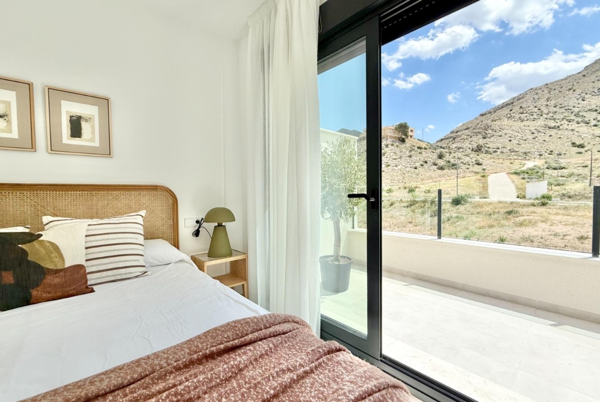Bright and airy 2-bedroom townhouse bedroom with modern decor and glass doors opening to a sunny terrace in Cox, Alicante.