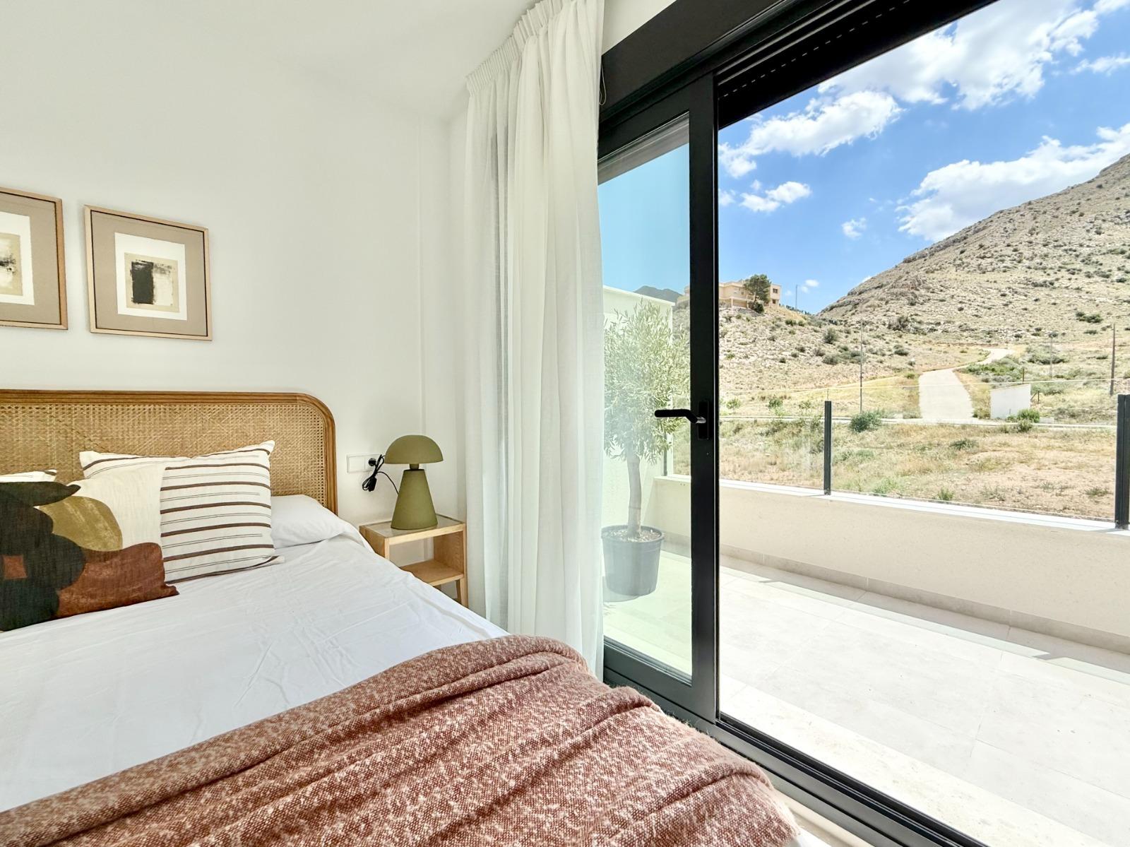 Bright and airy 2-bedroom townhouse bedroom with modern decor and glass doors opening to a sunny terrace in Cox, Alicante.