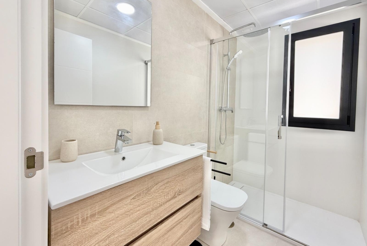 Bright modern bathroom with sleek vanity and glass shower in affordable 2-bedroom townhouse in Cox, Alicante.