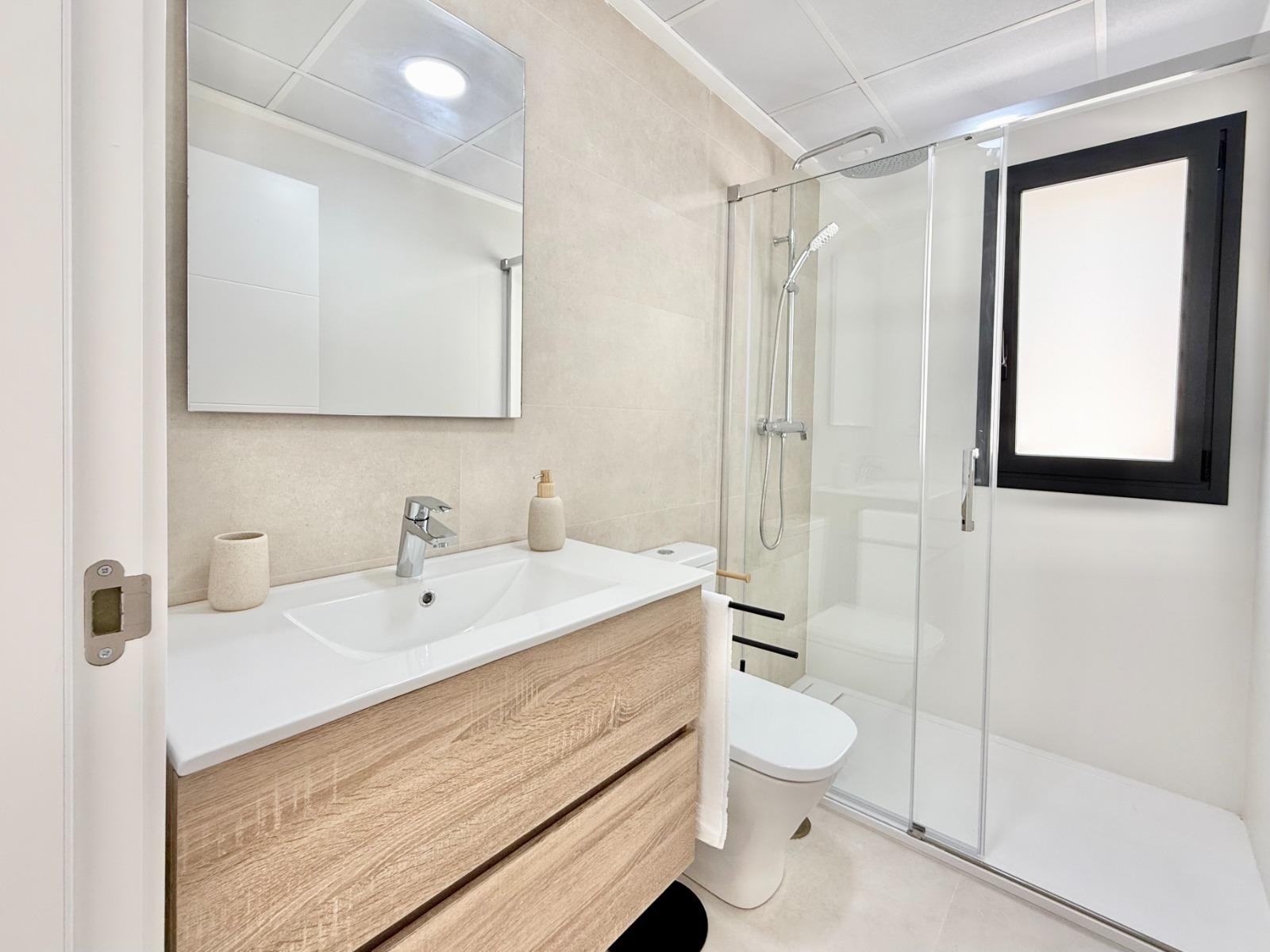 Bright modern bathroom with sleek vanity and glass shower in affordable 2-bedroom townhouse in Cox, Alicante.