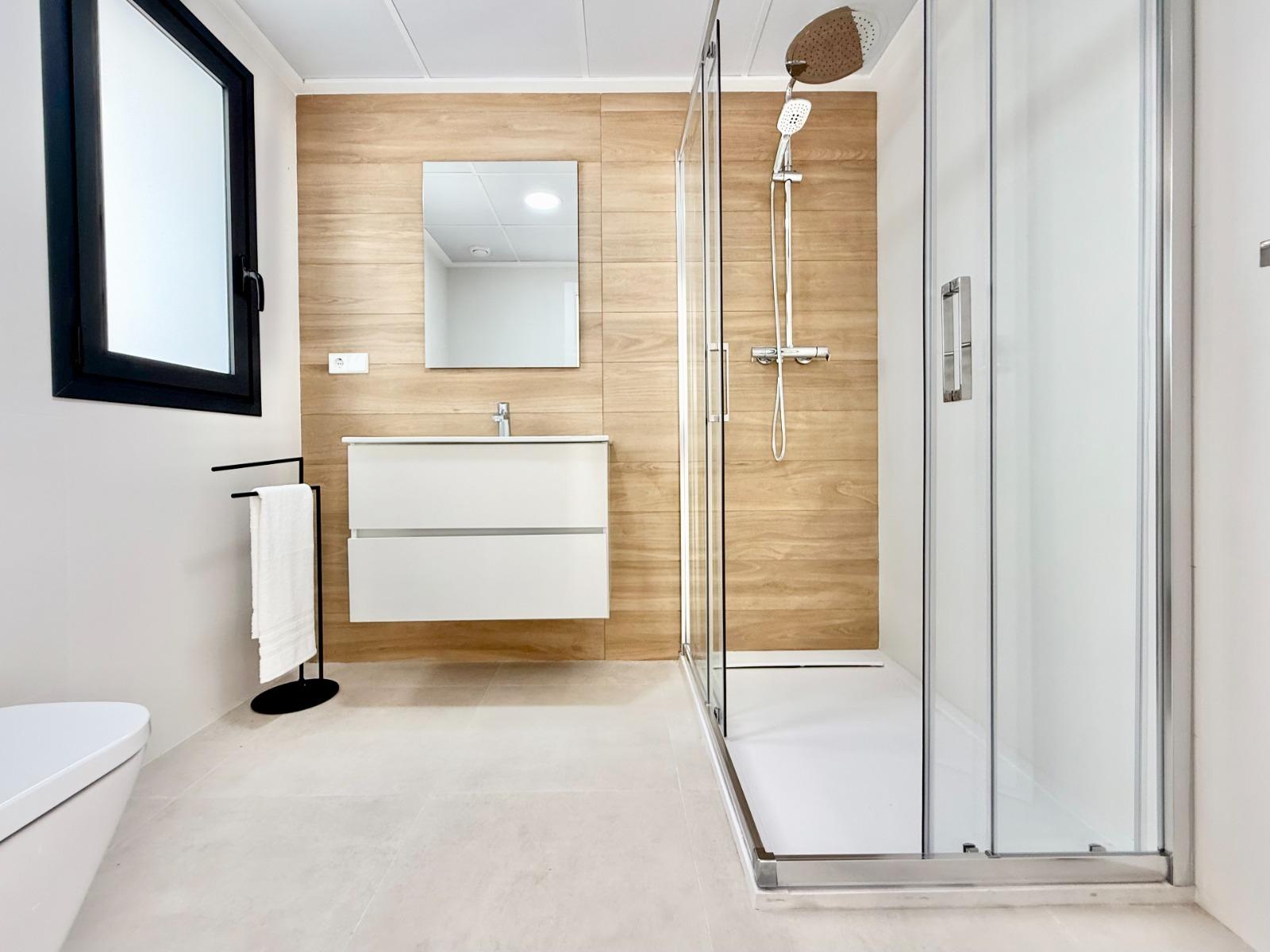 Modern, bright bathroom with sleek shower and wood-accented walls in a new 2-bedroom townhouse in Cox, Alicante