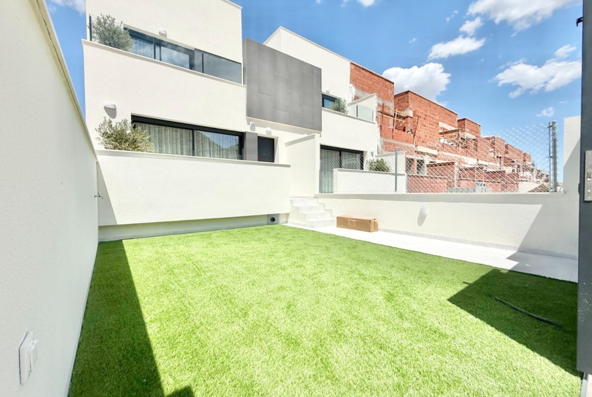 Bright, secluded garden space of spacious new build 3-bedroom townhouse in Cox, Alicante, with modern white exterior walls.
