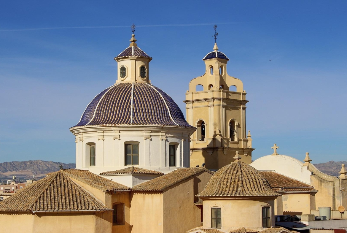 Historic church domes with tiled roofs under a clear sky, viewed near the luxury 3-bedroom townhouse in Cox, Alicante.