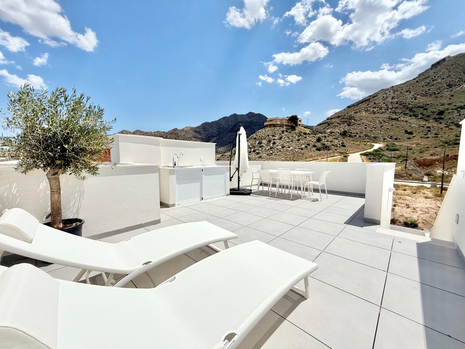 Spacious sun-drenched solarium with modern outdoor kitchen and loungers in a new 3-bedroom townhouse in Cox, Alicante.