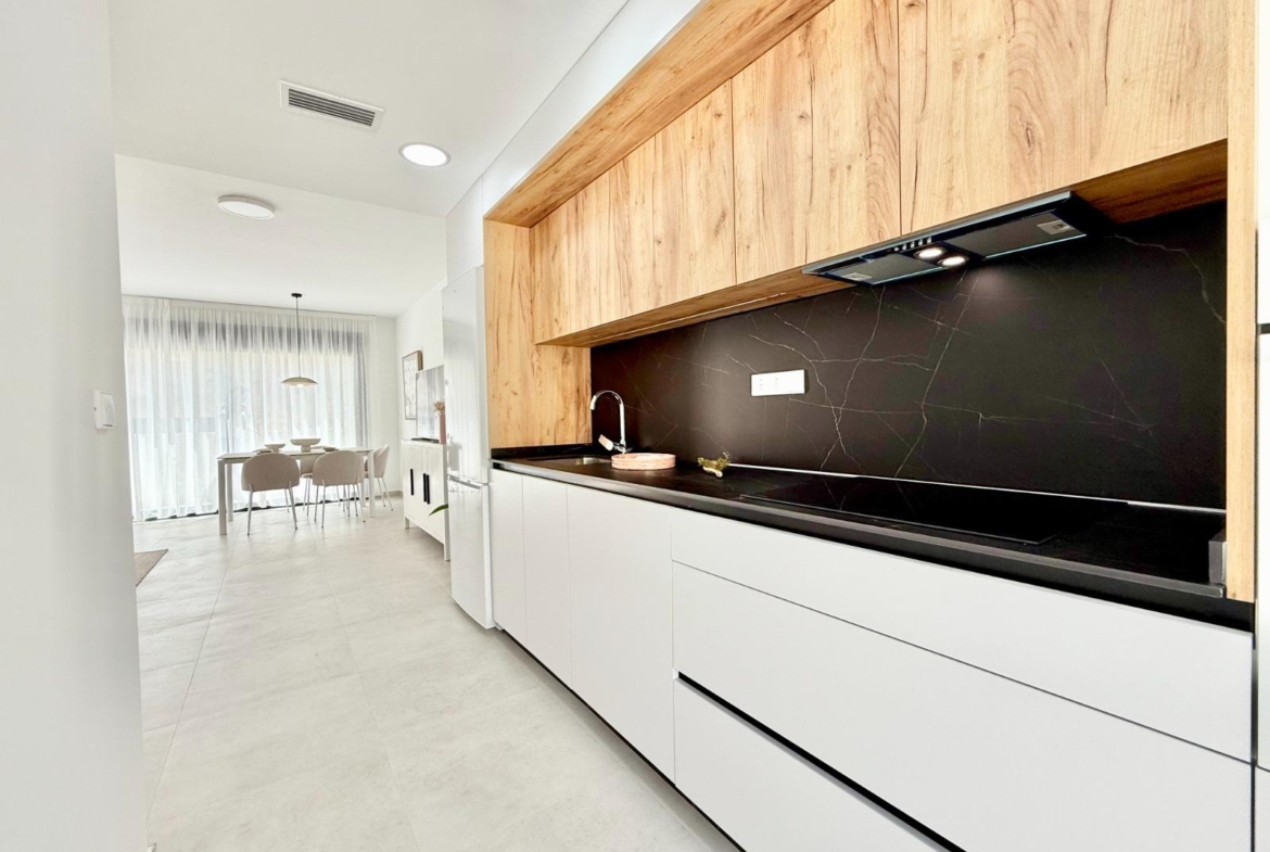 Bright modern kitchen with sleek black countertop and wood cabinets in spacious 3 bedroom townhouse in Cox, Alicante.
