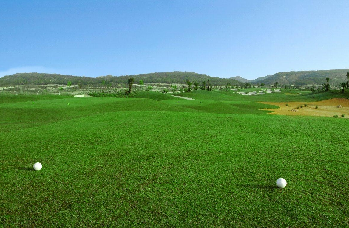 Lush, rolling golf course fairway with distant sand traps and hills, offering serene views near the villa in Vistabella Golf Orihuela.