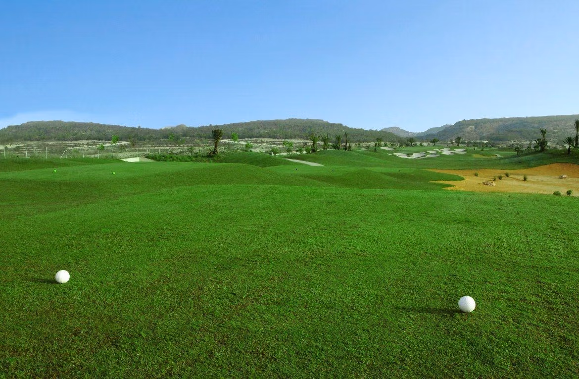 Lush, rolling golf course fairway with distant sand traps and hills, offering serene views near the villa in Vistabella Golf Orihuela.