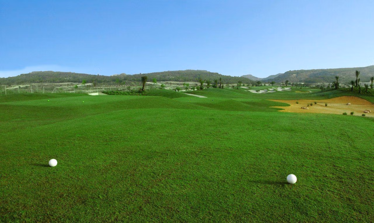 Lush, rolling golf course fairway with distant sand traps and hills, offering serene views near the villa in Vistabella Golf Orihuela.