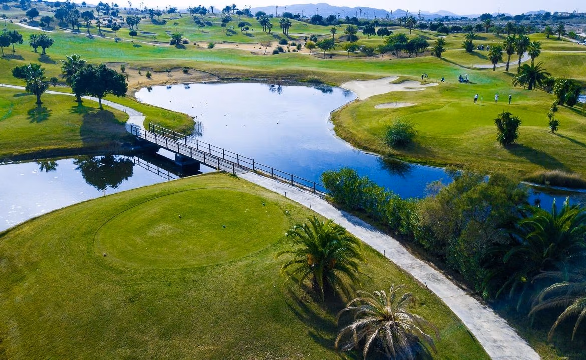 Panoramic sunlit golf course with tranquil water features and lush greenery near spacious family villa in Vistabella Golf, Orihuela.