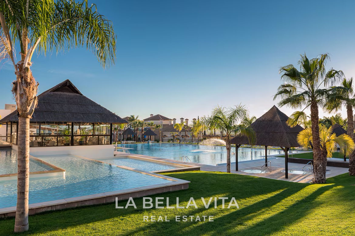 Lush landscaped gardens with crystal-clear private pool and thatched solarium at luxury single-storey villa in Hacienda del Álamo Golf Resort Murcia