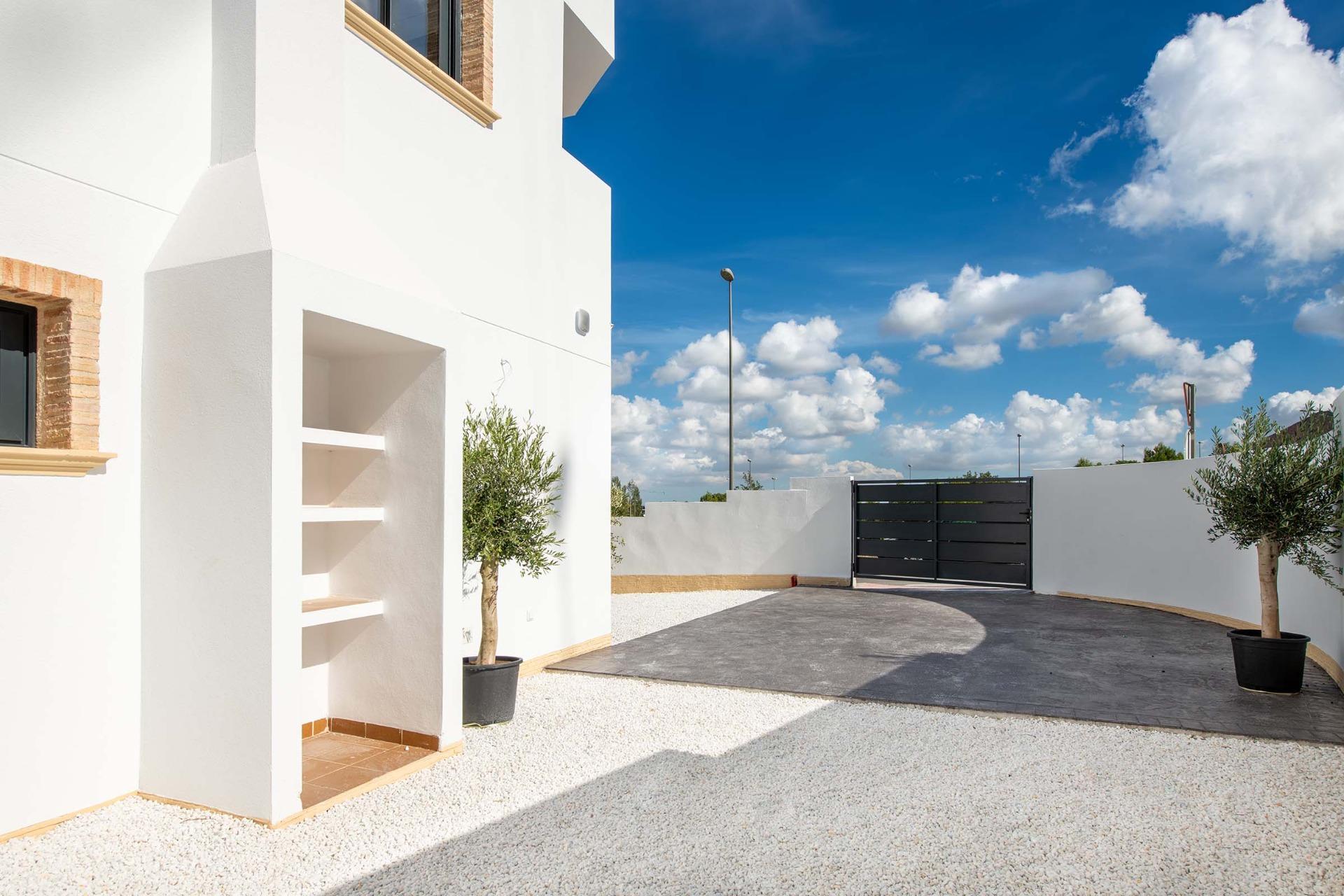 Bright, spacious exterior courtyard with modern white walls and gated driveway of a 2-bedroom top floor bungalow in Cox, Alicante.