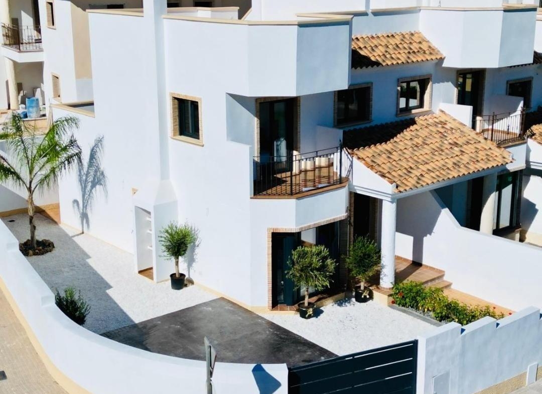 Modern whitewashed 3-bedroom ground floor bungalow with terracotta roof in sunlit Cox, Alicante residential complex.