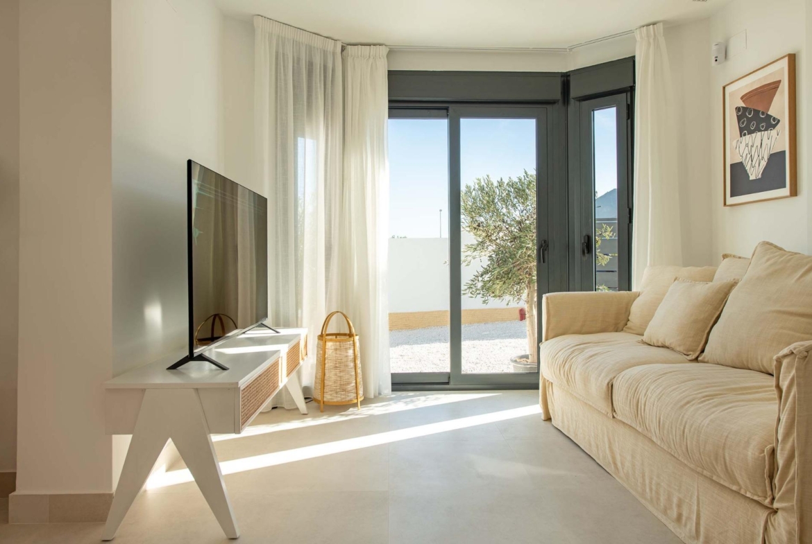 Bright and airy living room with modern decor and large glass doors opening to a sunny terrace in the Cox townhouse, Alicante.