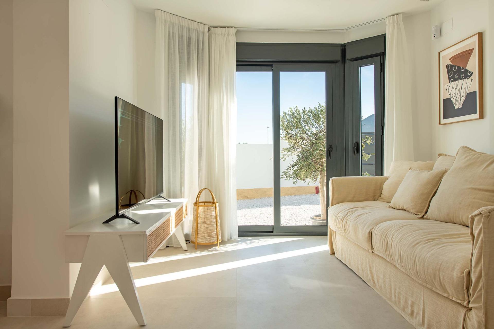 Bright and airy living room with modern decor and large glass doors opening to a sunny terrace in the Cox townhouse, Alicante.
