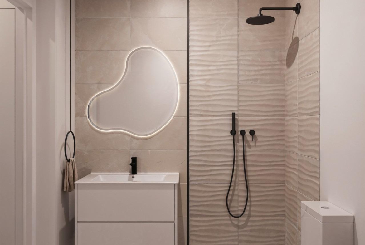Elegant modern bathroom with sculptural backlit mirror and sleek walk-in shower in 3-bedroom ground floor apartment, San Miguel de Salinas
