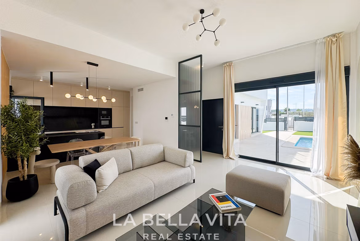 Bright, modern open-plan living area with sleek kitchen and glass doors opening to private pool terrace in San Miguel de Salinas villa.